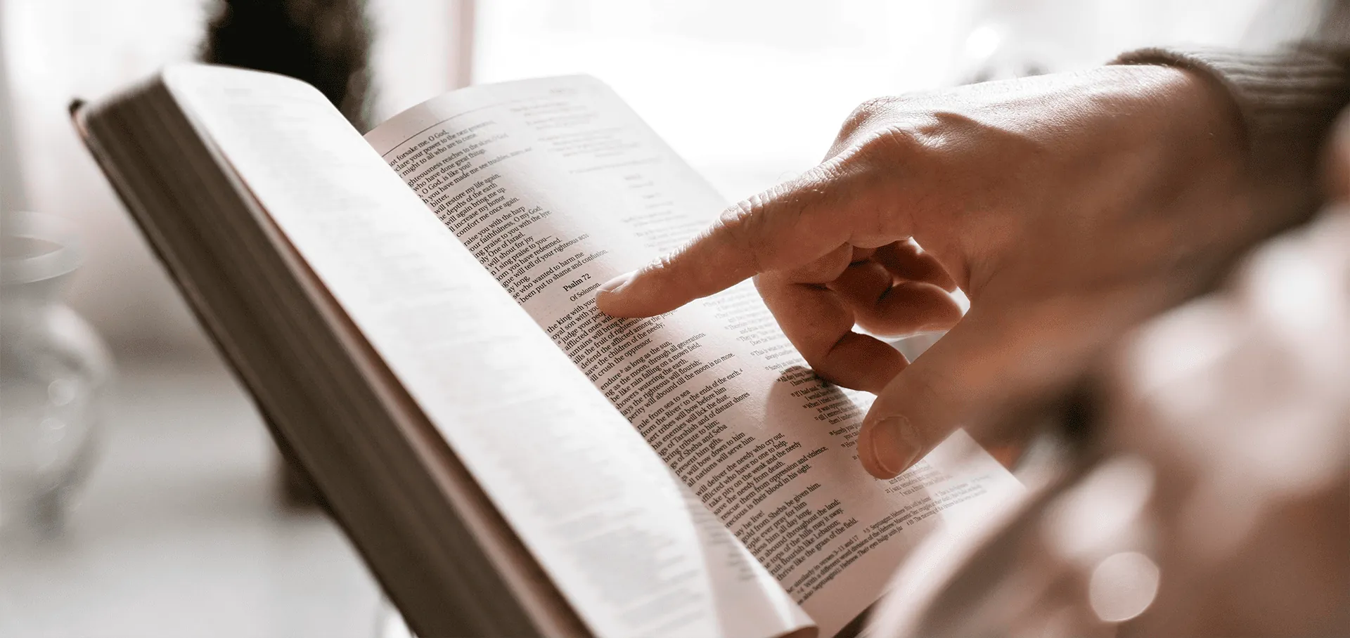 Mão acompanhando a leitura da Bíblia